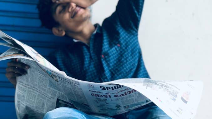 photo-of-a-man-sitting-while-holding-newspaper