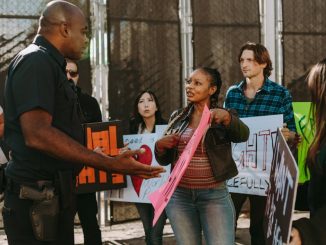 a-diverse-group-of-people-engaged-in-a-peaceful-protest-outdoors-discussing-with-a-police-officer-1