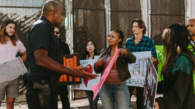 a-diverse-group-of-people-engaged-in-a-peaceful-protest-outdoors-discussing-with-a-police-officer-1